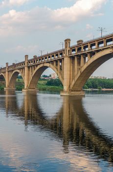 road and rail split-level bridge over the river on a background of blue sky in the city