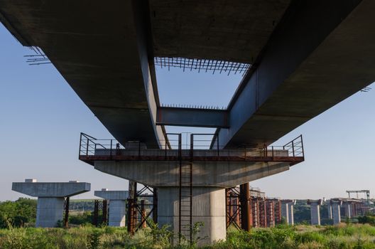 the construction of a bridge across the river with the supports, structural elements, cranes