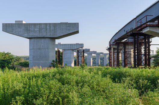 the construction of a bridge across the river with the supports, structural elements, cranes