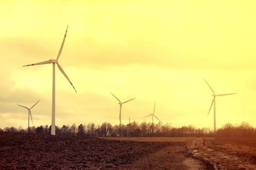 Windmills on the plowed field. Vintage instagram picture. Alternative energy.