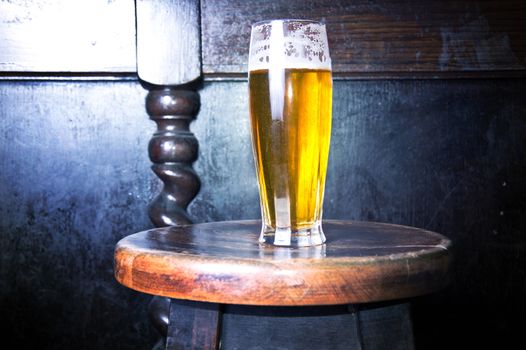 Alcohol conceptual image. Glass of fresh cold beer put on the bar chair.