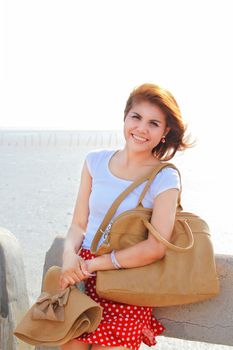 Happy lady at the beach with her brown hat and leather bag