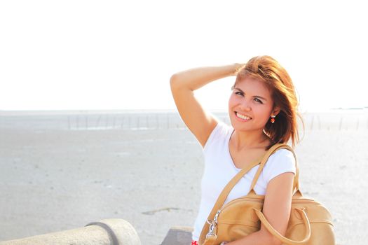 Happy lady at the beach with her brown leather bag