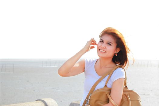 Happy lady at the beach with her brown leather bag