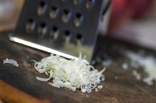 Grated cheese and grater on cutting board close up