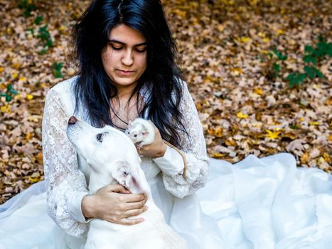 Latina teenage girl sitting outside in the autumn leaves with her pet dog and rat