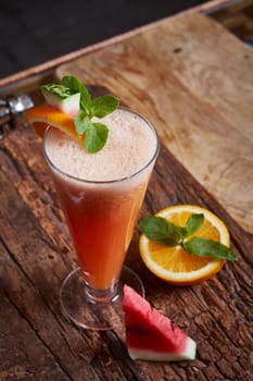 glass watermelon and orange smoothie with copy space on wooden background