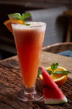 glass watermelon and orange smoothie with copy space on wooden background