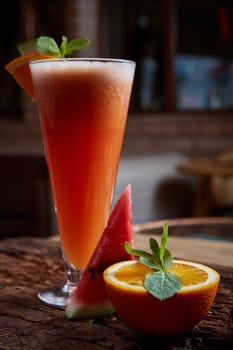 glass watermelon and orange smoothie with copy space on wooden background