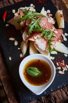 salad of fresh melon with thin slices of prosciutto, arugula leaves and balsamic sauce top view