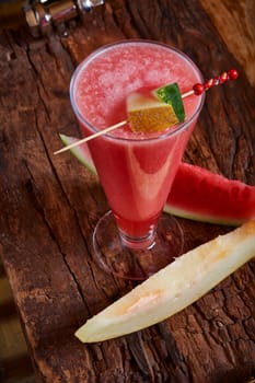 Healthy watermelon and melon smoothie with copy space on a wood background
