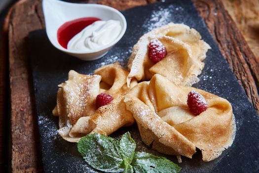 Crepes with raspberries with copy space on black background