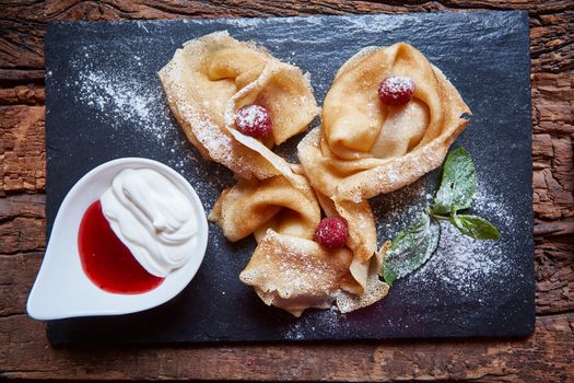 Crepes with raspberries with copy space on black background
