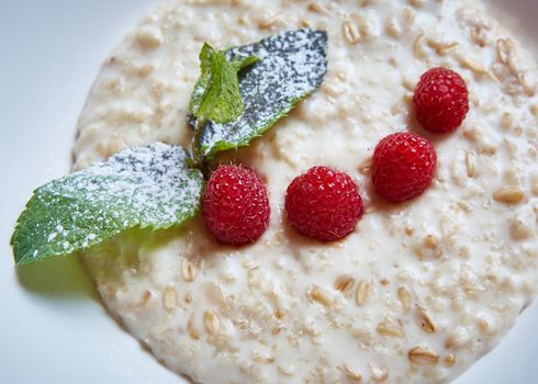 oatmeal with raspberries and mint in white plate