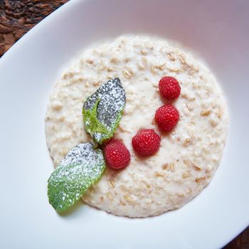 oatmeal with raspberries and mint in white plate