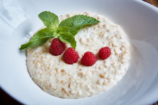 oatmeal with raspberries and mint in white plate