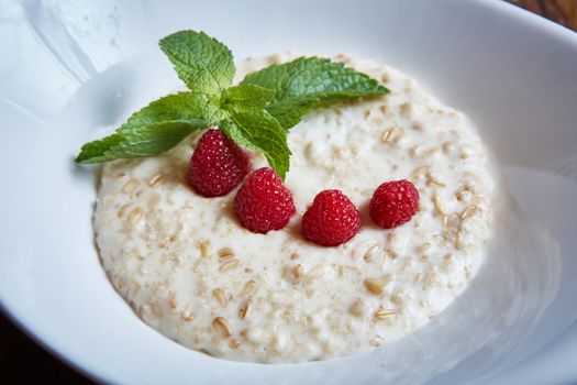 oatmeal with raspberries and mint in white plate