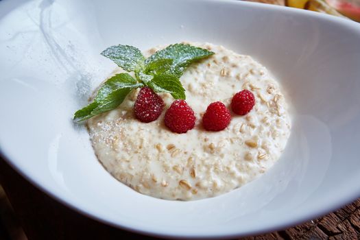 oatmeal with raspberries and mint in white plate