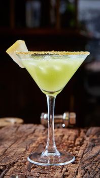 Green margarita melon cocktail with copy space on wooden background.