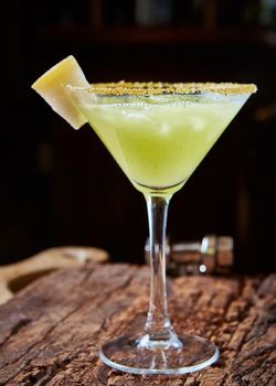 Green margarita melon cocktail with copy space on wooden background.