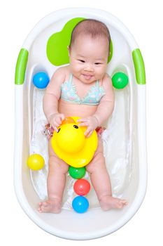 Asian baby girl taking a bath in white tub and playing duck and have different color of plastic balls.