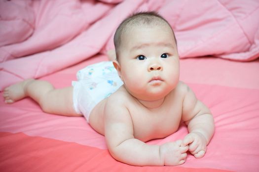 Asian baby girl weared daiper and be inattentive on pink bed