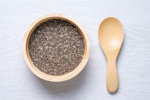 chai seed in wooden bowl and wooden spoon on white wooden table
