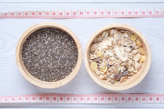 Muesli and chai seed in wooden bowl with tape measure