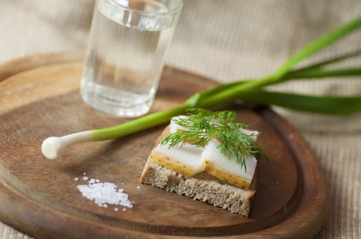 Sandwich with salted lard on rye bread served with vodka, green garlic