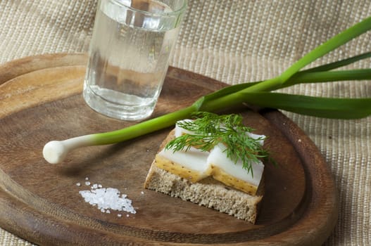 Sandwich with salted lard on rye bread served with vodka, green garlic