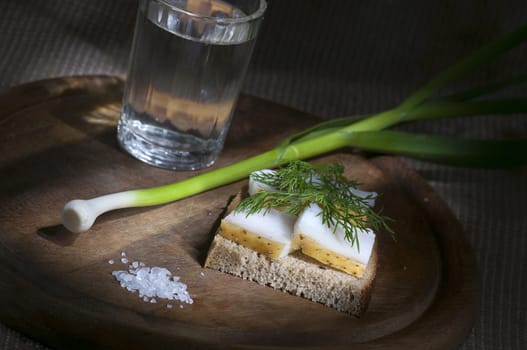 Sandwich with salted lard on rye bread served with vodka, green onion and garlic