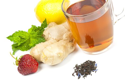 Cup of black tea served with ginger, lemon, strawberry and mint isolated on white