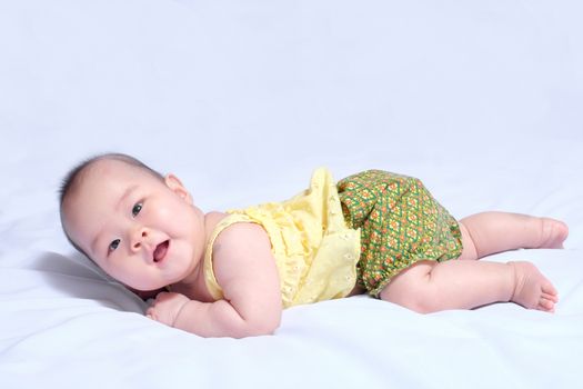 asian baby girl in traditional thai dress, she lie prone, smile , and looking at camera