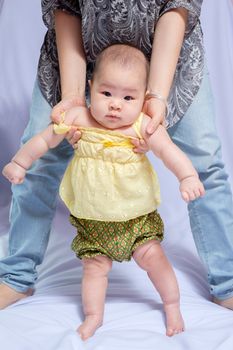 asian baby girl in traditional thai dress, her mom try to pull her stand and  she looking at the camera