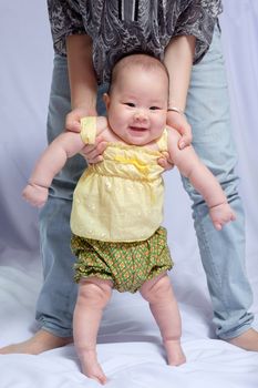 asian baby girl in traditional thai dress, her mom try to pull her stand, she smile and happy with her mom.