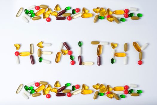 Healthy words made by pills of vitamin and medicine on white background