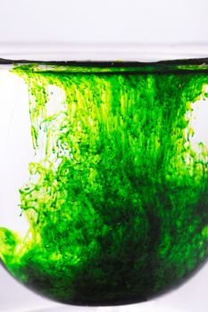 Green food coloring powder spread in glass of water