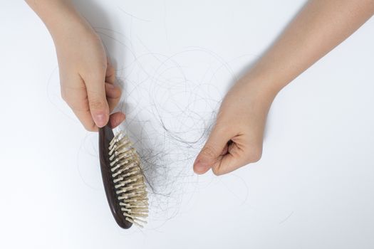 Hair loss in woman hands and bruch, on white background, women postpartum defluvium 