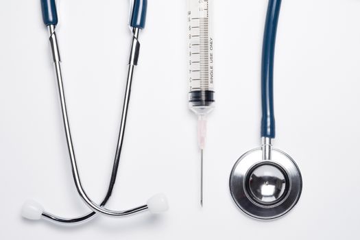 Blue stethoscope and syringe on white background