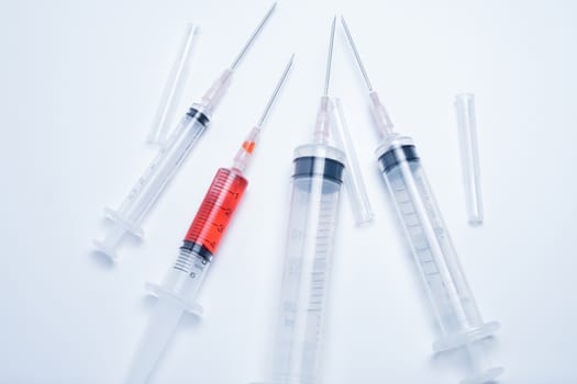 syringes with red vaccine on white background. this photo in cold mood tone.