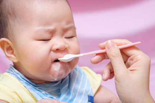 Mother feeding her asian thai baby girl a milk with spoon