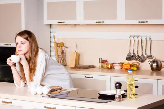 Girl thinking drinking tea in the kitchen