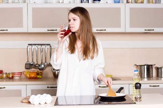 girl in a white men's shirt drinking red wine near the pans