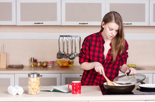 Girl with long flowing hair in a red shirt male prepares in the kitchen