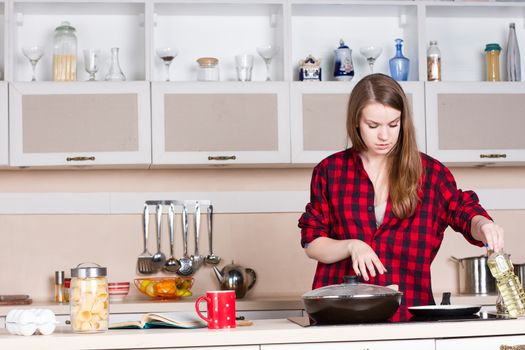 Girl with long flowing hair in a red shirt male prepares in the kitchen