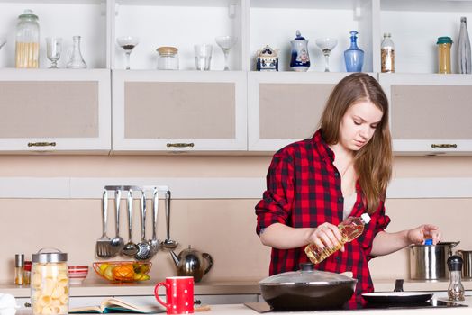 Girl with long flowing hair in a red shirt male prepares in the kitchen. Horizontal framing