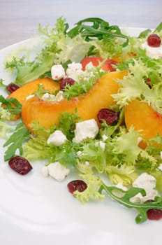 Salad of lettuce and arugula with peaches, feta cheese, cranberries