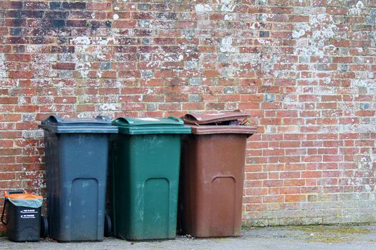 Trash can dustbins outside against brick wall 