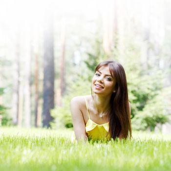 beautiful young woman in yellow dress lying on grass