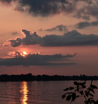 Sun descends through cloudy sky over northern lake